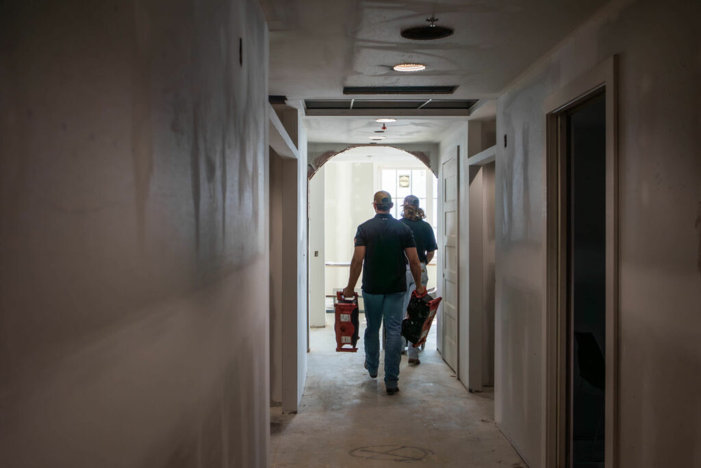 men carrying tools walking in a hallway
